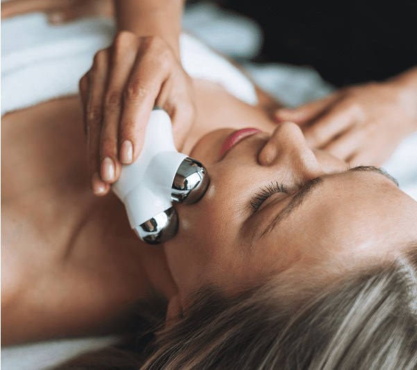 Woman receiving facial massage with beauty device.