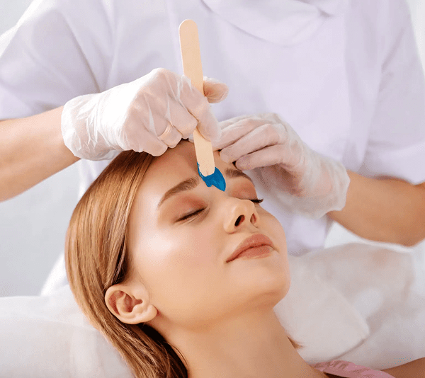 Woman receiving a facial waxing treatment.